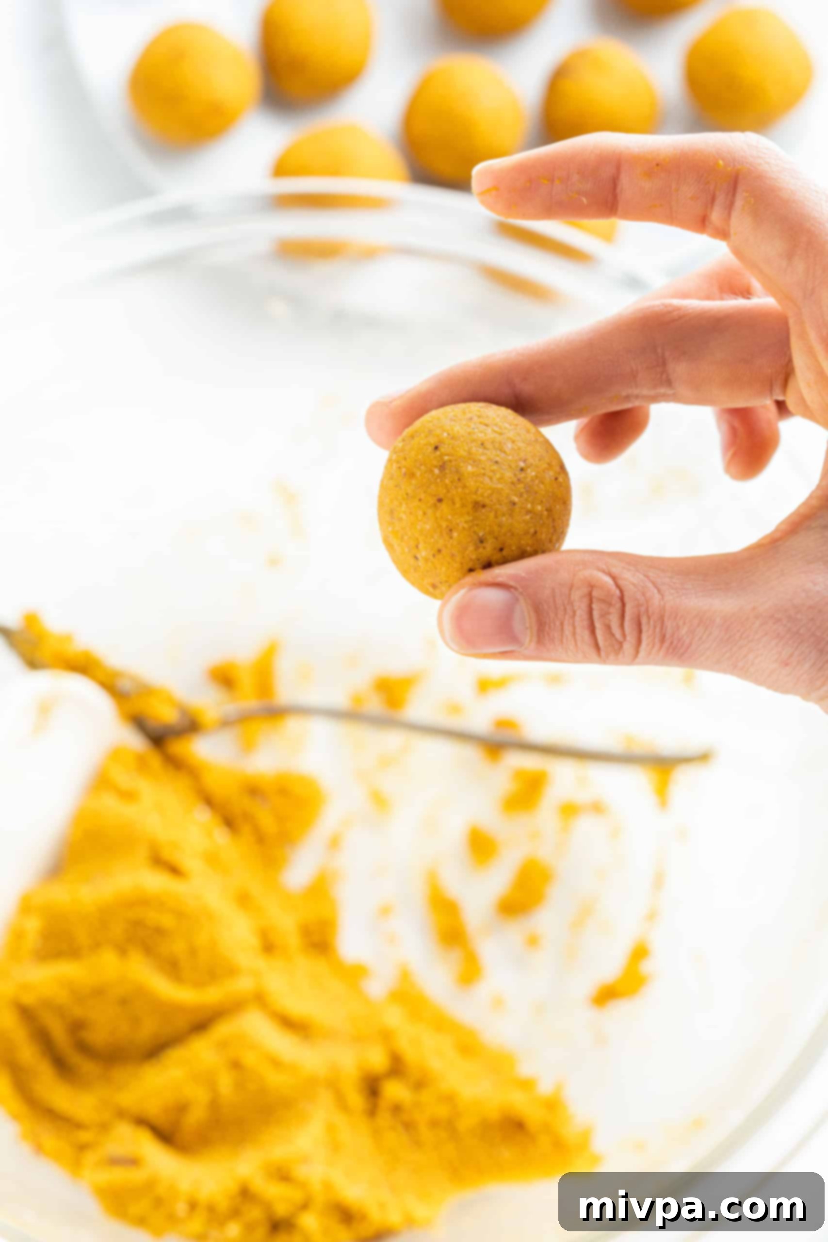 No-Bake Chocolate Pumpkin Truffles (Gluten-Free, Vegan) A hand gently holding a perfectly rolled pumpkin truffle ball, showcasing its smooth texture.