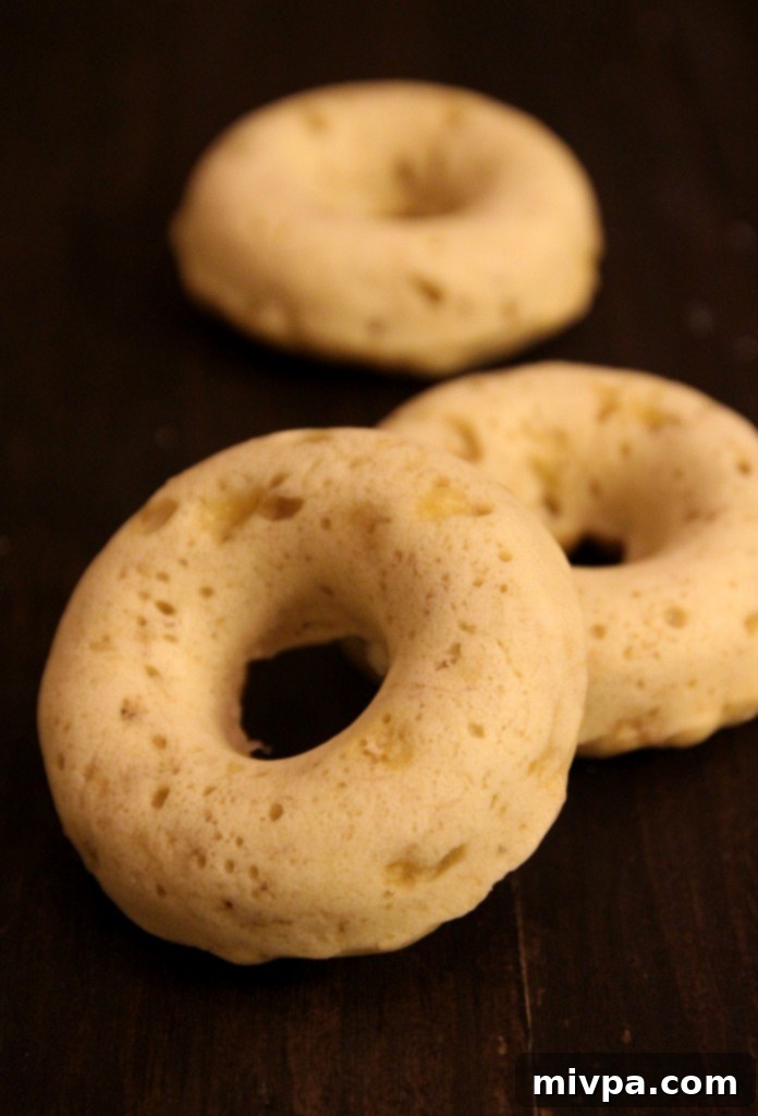 Baked Banana Doughnuts with Chocolate Glaze and Almonds on a rustic wooden board