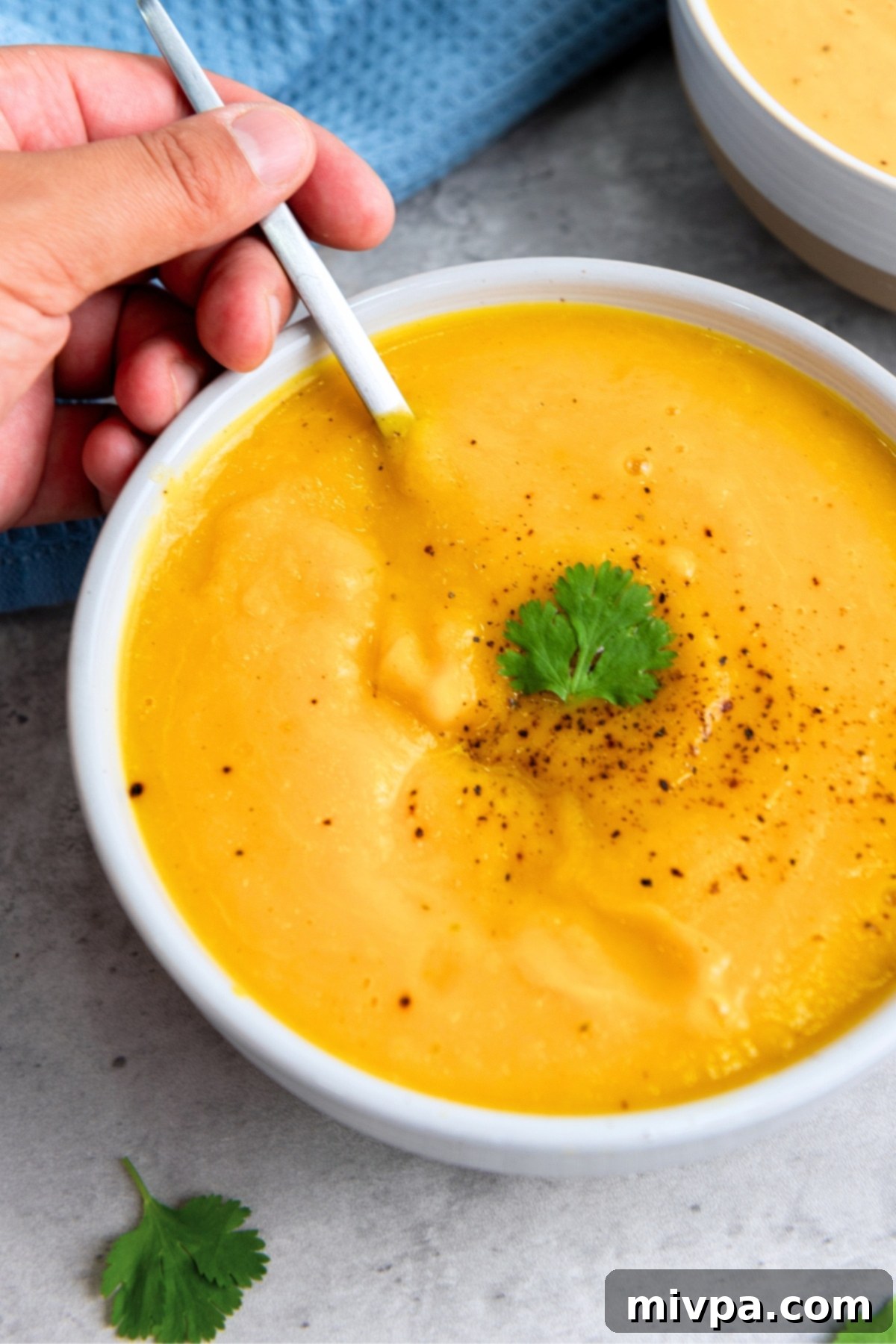 Dairy-Free Butternut Squash Soup Scooping up butternut squash soup from a bowl.