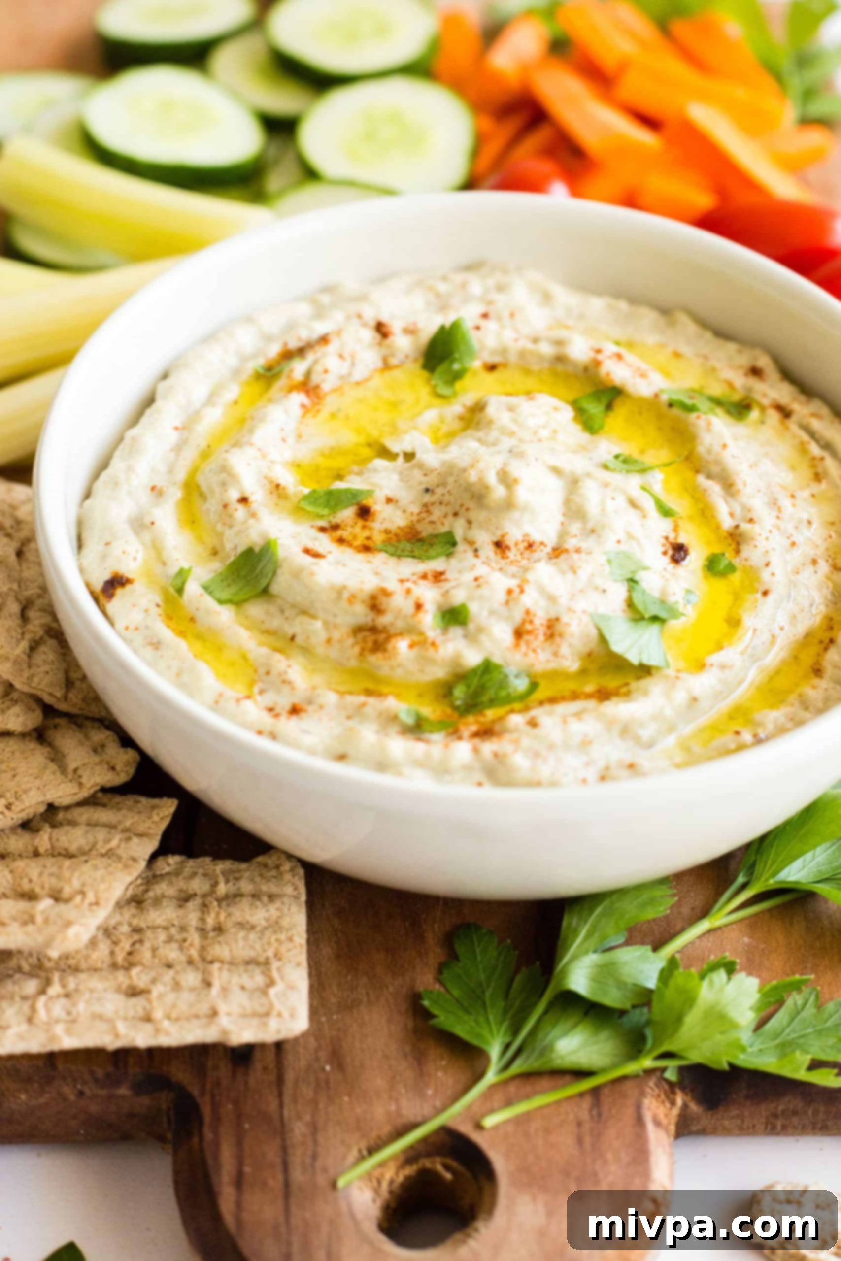 A white bowl with baba ganoush on a wooden board.