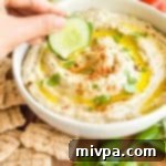 Dipping a cucumber slice into a bowl of baba ganoush