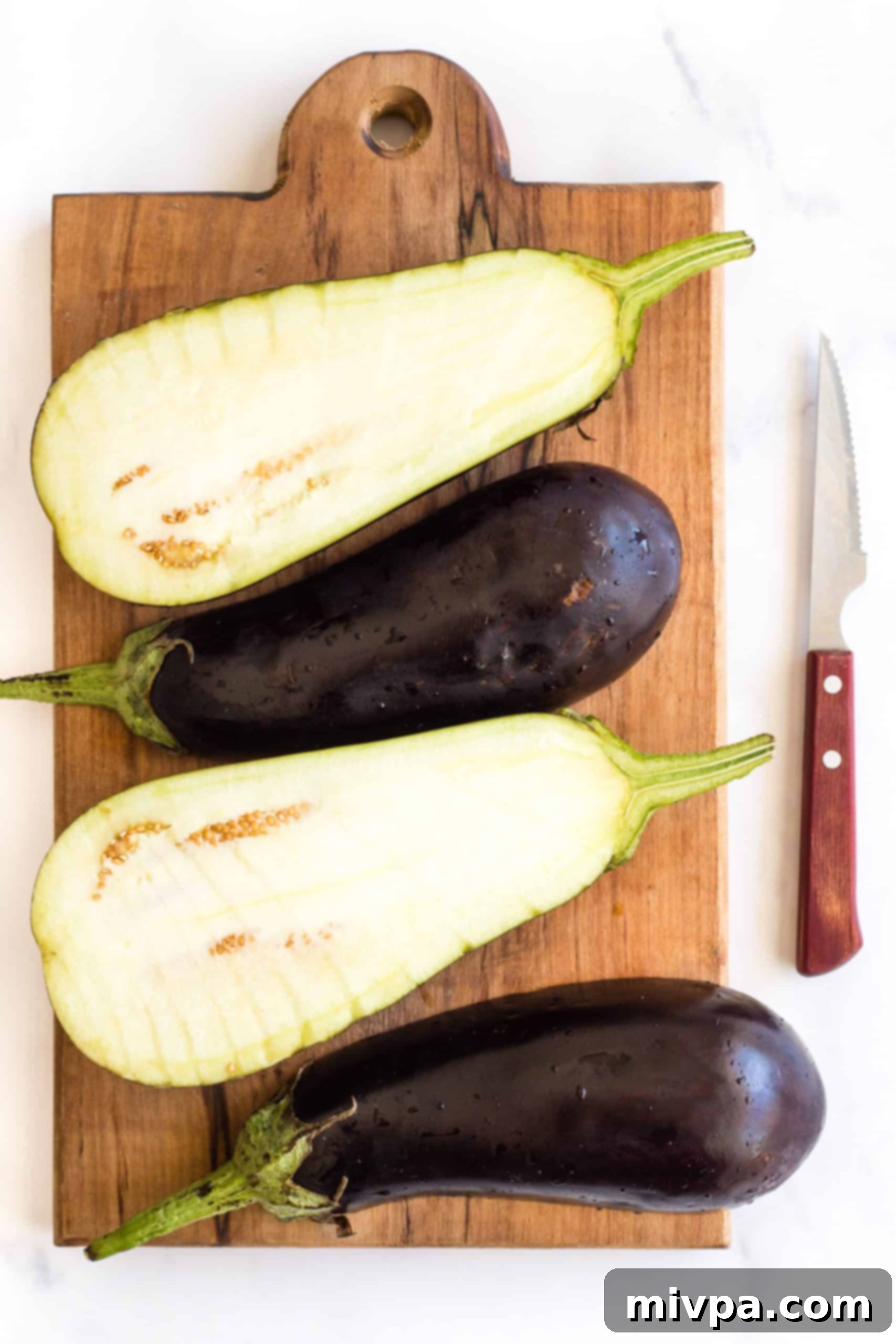 Eggplant halves on a wooden board.