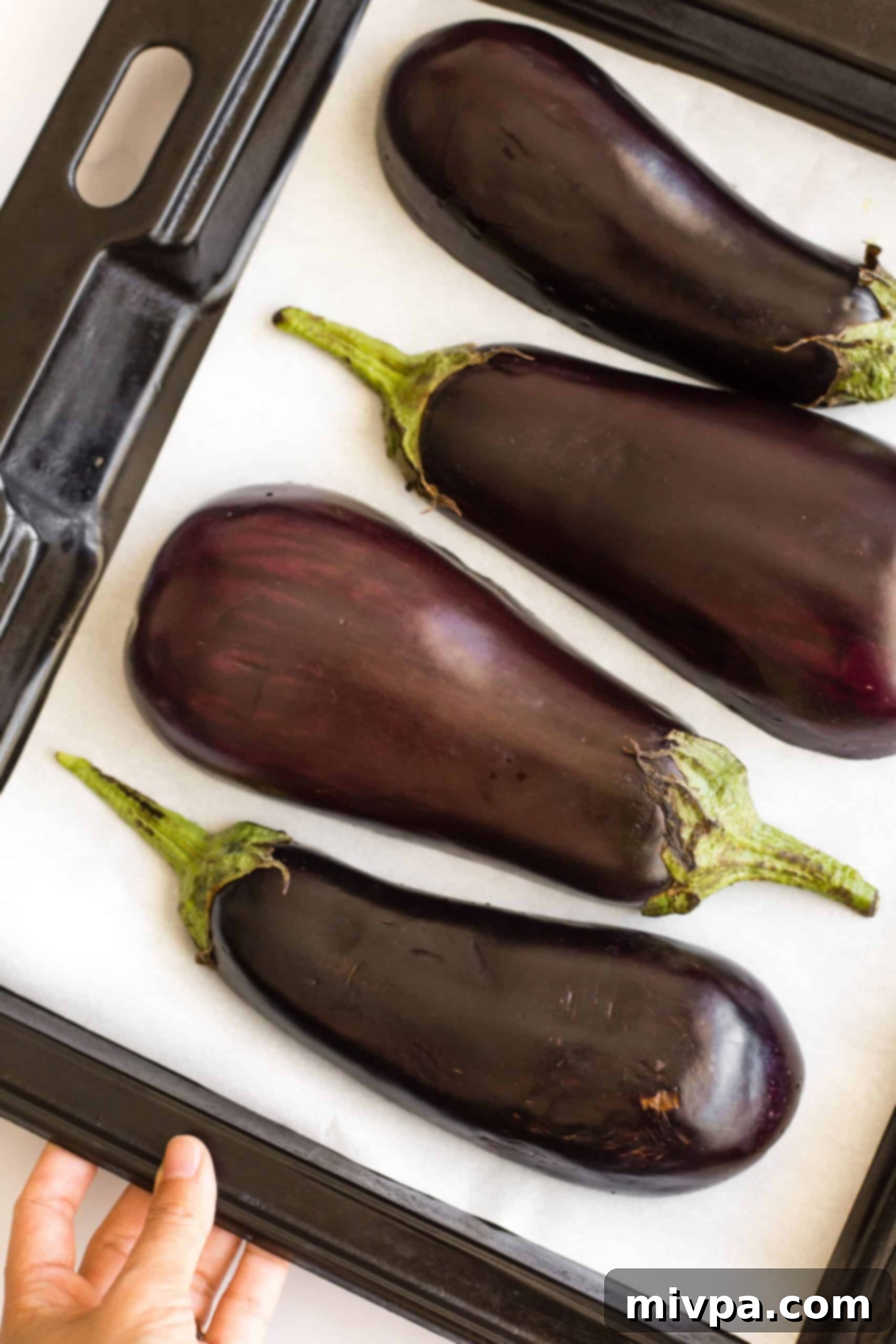 Eggplant halves on a parchment-lined baking sheet.