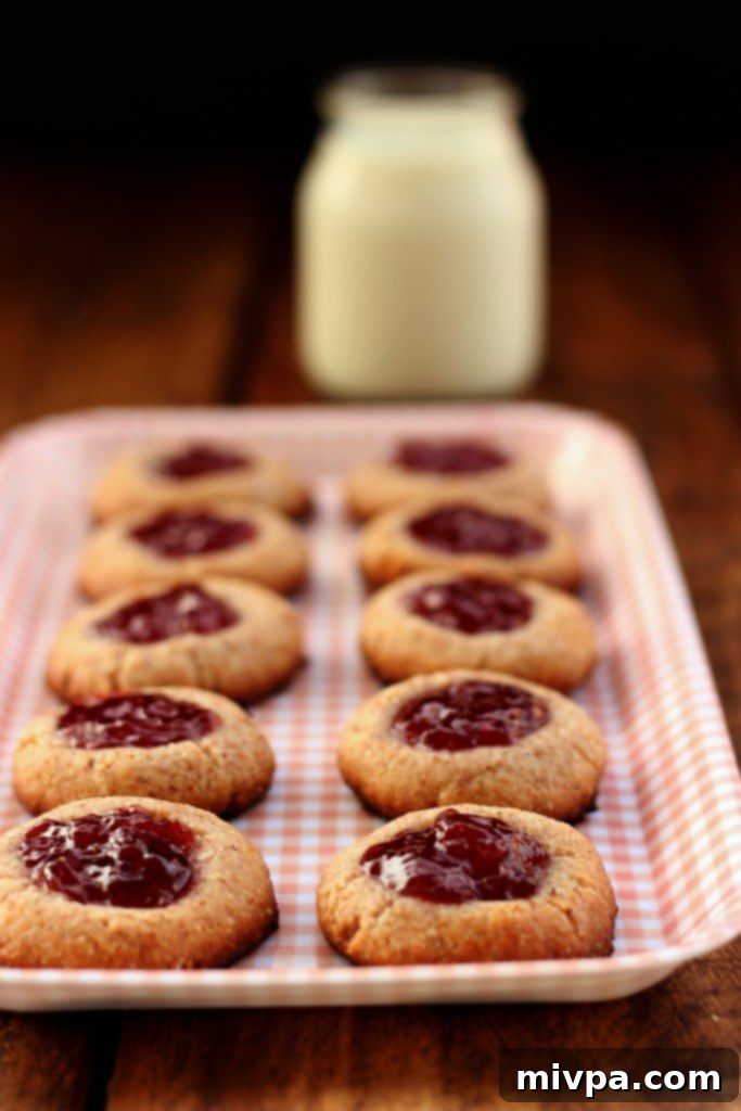 Berry-Kissed Grain-Free Thumbprints 4 Stacked grain-free strawberry thumbprint cookies on a plate