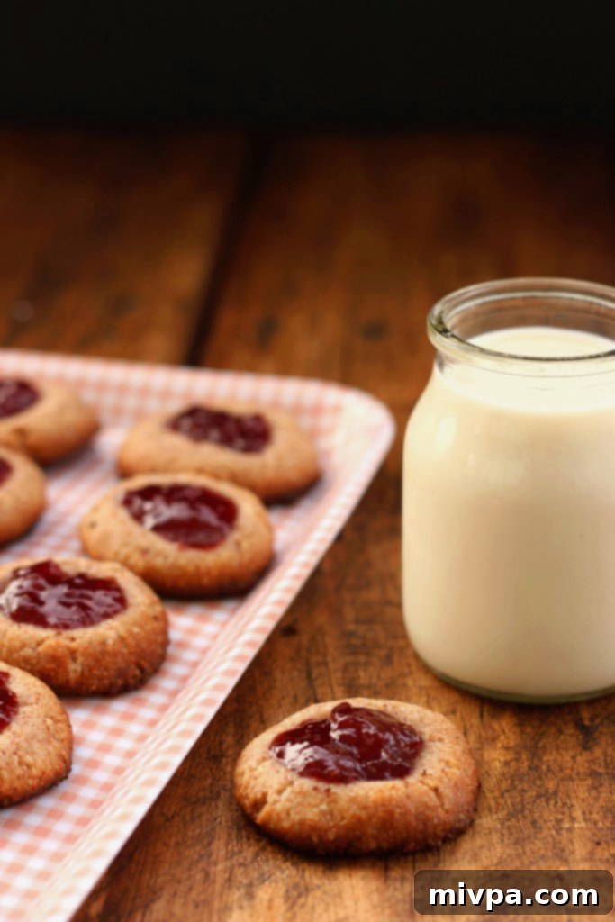 Berry-Kissed Grain-Free Thumbprints 7 Close up of a hand holding a grain-free strawberry thumbprint cookie