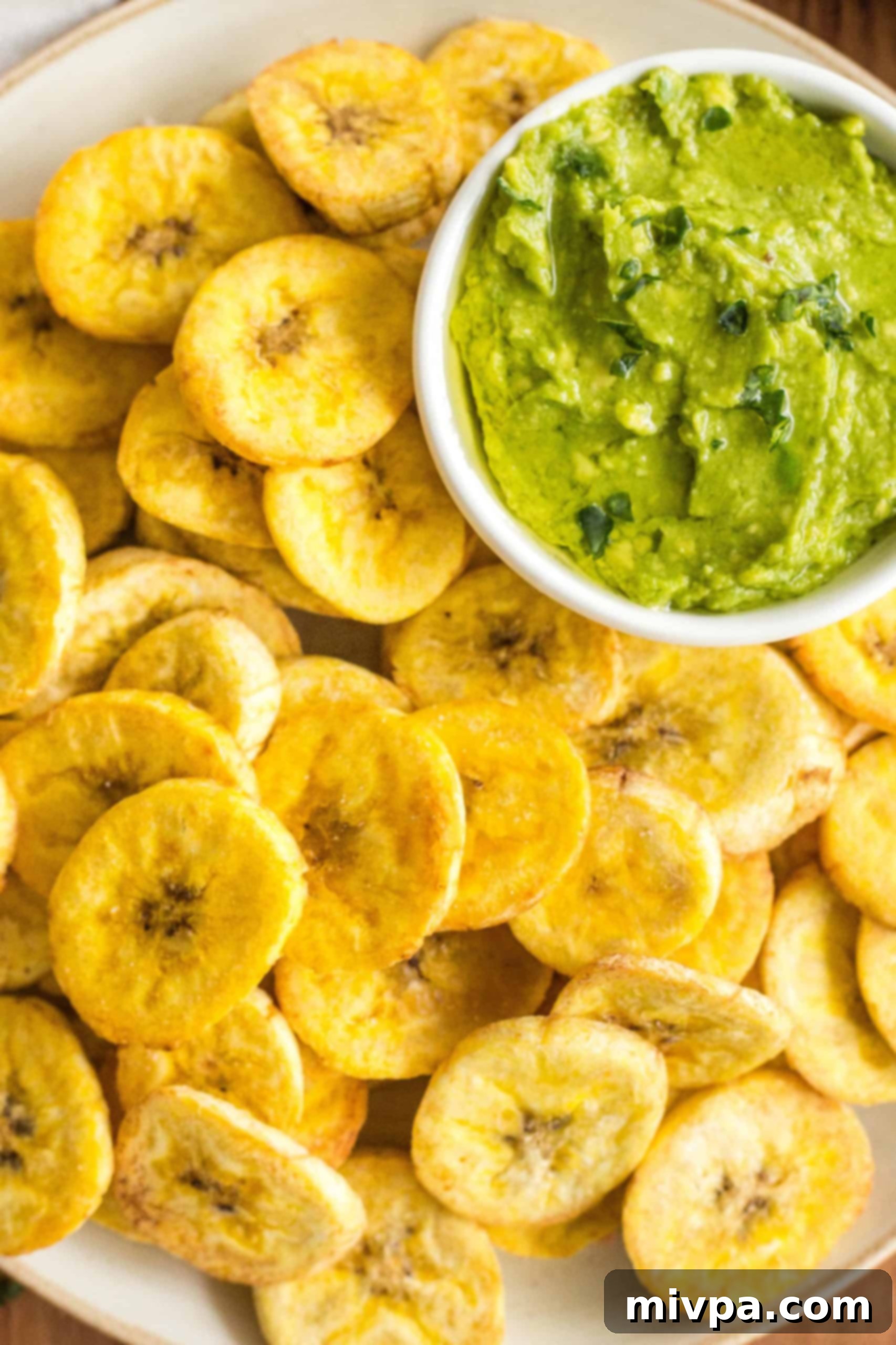 Close up shot of air fryer plantain chips and a bowl of guacamole.