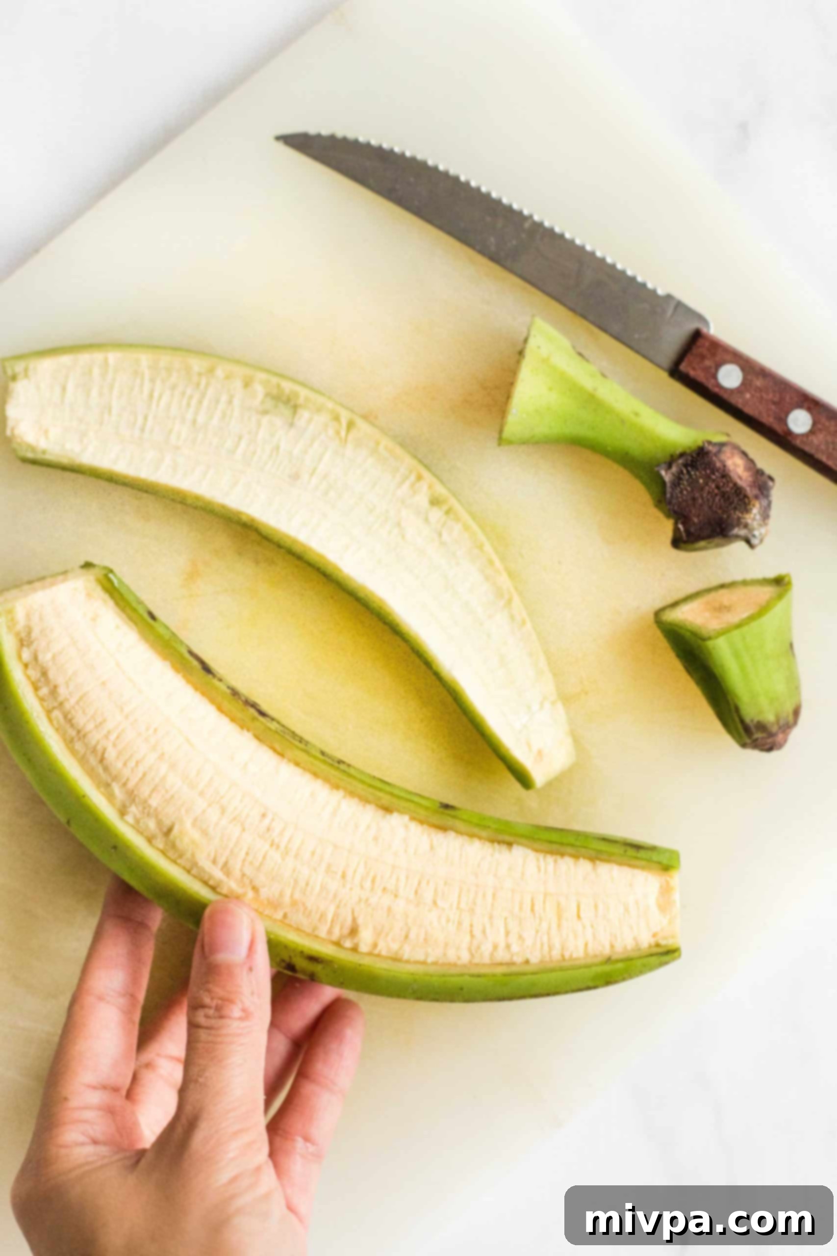 Holding a half-peeled green plantain.