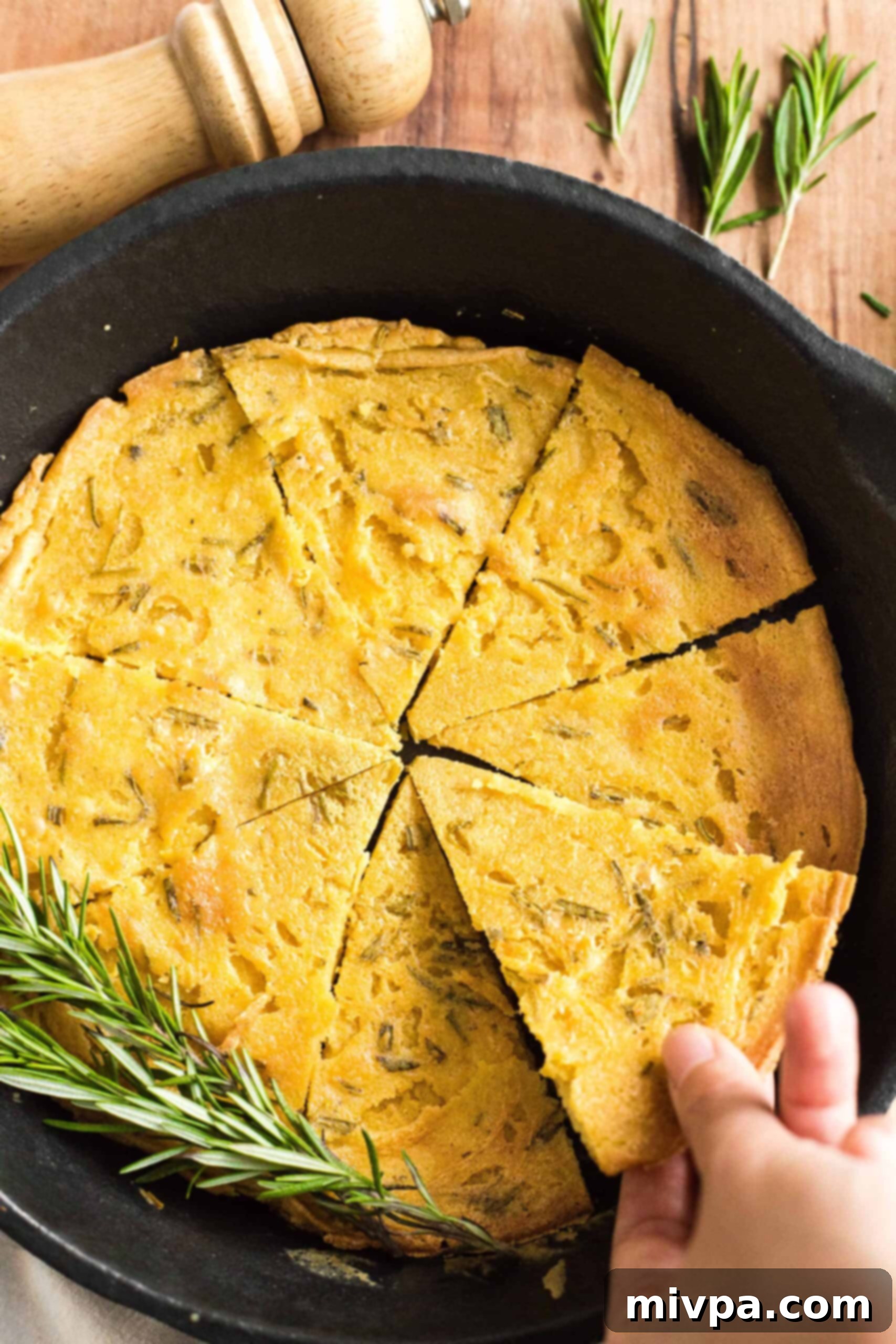Easy Farinata Recipe - Chickpea Flatbread (Gluten-Free, Vegan) Hand reaching for a slice of golden-brown farinata from a hot cast iron skillet, showcasing its crispy edge.