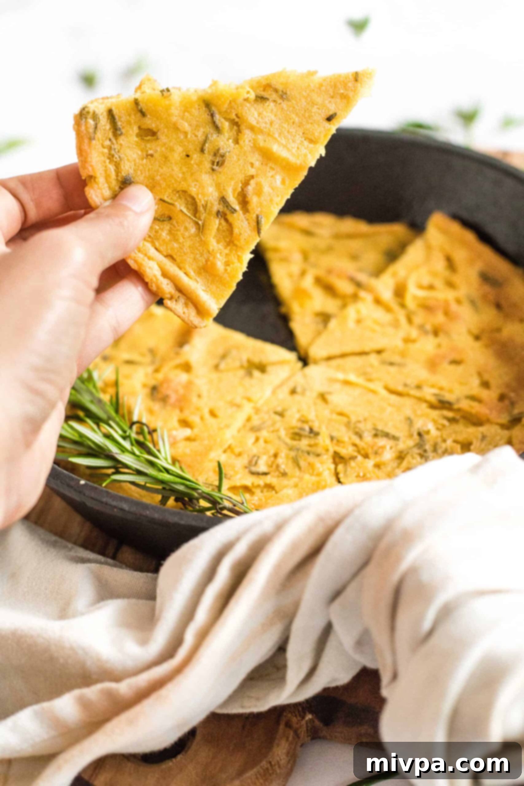 Easy Farinata Recipe - Chickpea Flatbread (Gluten-Free, Vegan) Holding up a golden slice of farinata (chickpea flatbread) against a blurred background, emphasizing its texture.