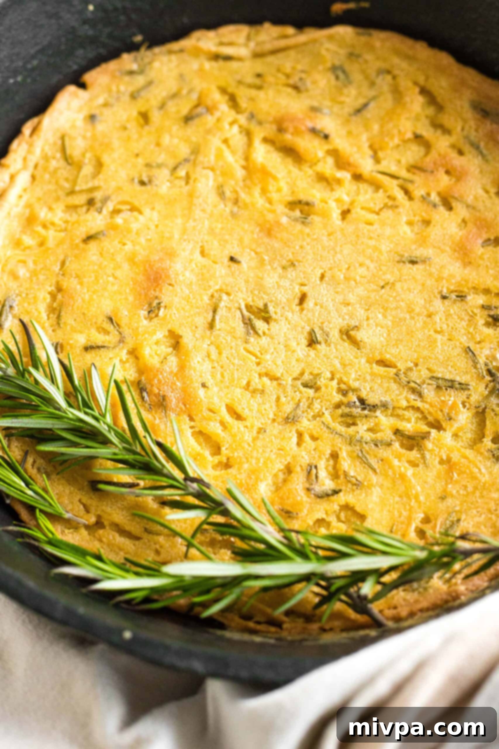 Easy Farinata Recipe - Chickpea Flatbread (Gluten-Free, Vegan) Fresh rosemary sprigs artfully arranged on top of a hot, baked farinata in a cast iron skillet.