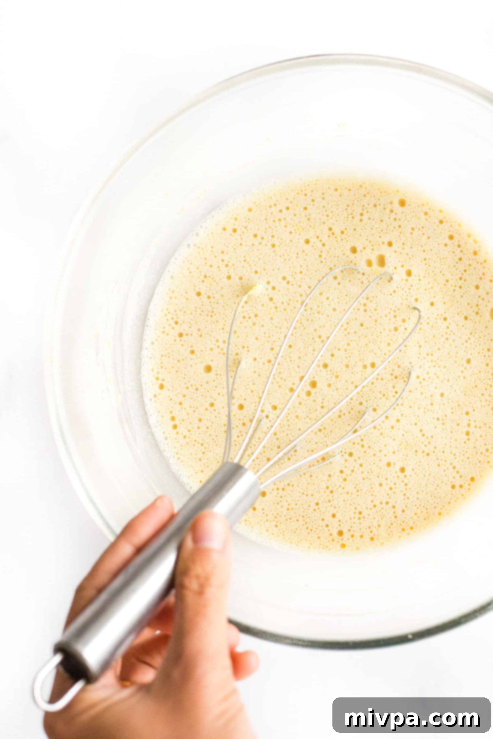 Easy Farinata Recipe - Chickpea Flatbread (Gluten-Free, Vegan) Whisking chickpea flour, salt, and warm water together in a clear glass bowl to form a smooth batter.