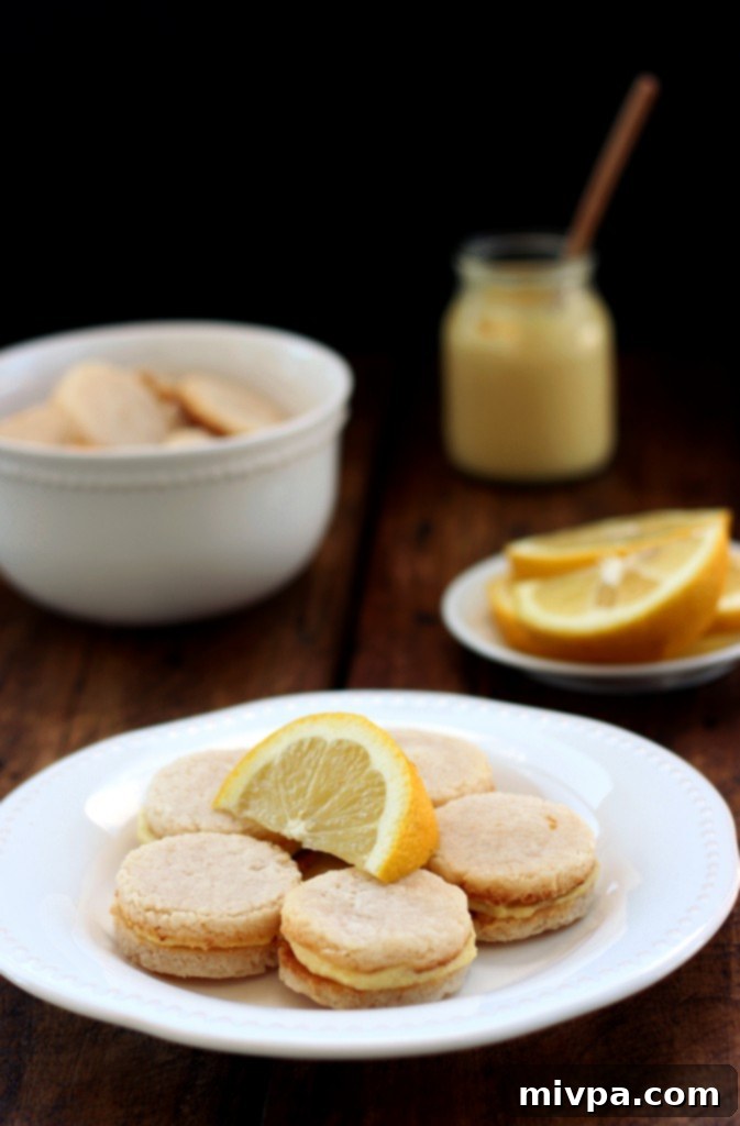 Grain-free Lemon Sandwich Cookies – Hands rolling out the cookie dough on parchment paper, dusted with flour.