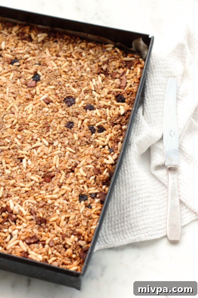 Freshly baked granola mixture pressed down in a baking sheet, with a spoon visible.