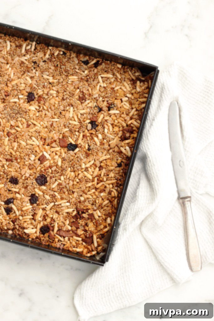 Top down view of healthy homemade granola mixture in a baking sheet, showing its texture before cutting.