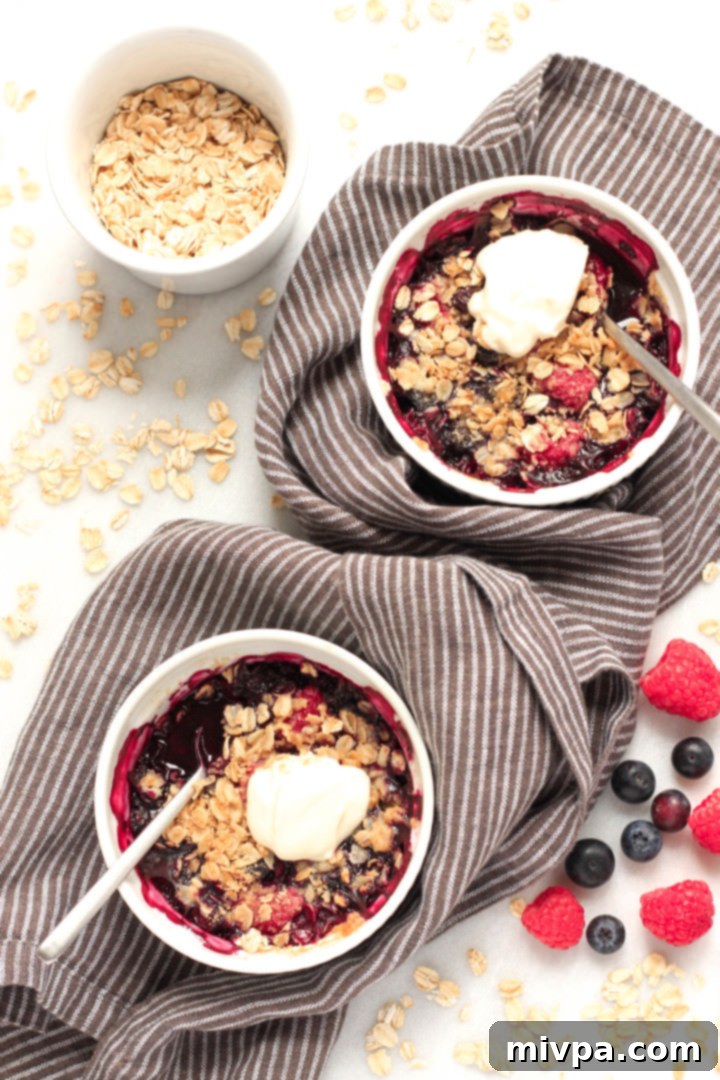 Gluten Free Vegan Berry Crisp 2 Two ramekins filled with warm, bubbling gluten-free berry crisp, topped with a golden oat crumble and ready to be served on a kitchen towel.