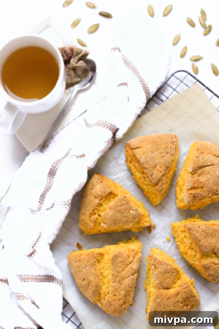 Freshly baked scones on parchment paper alongside a mug of tea.