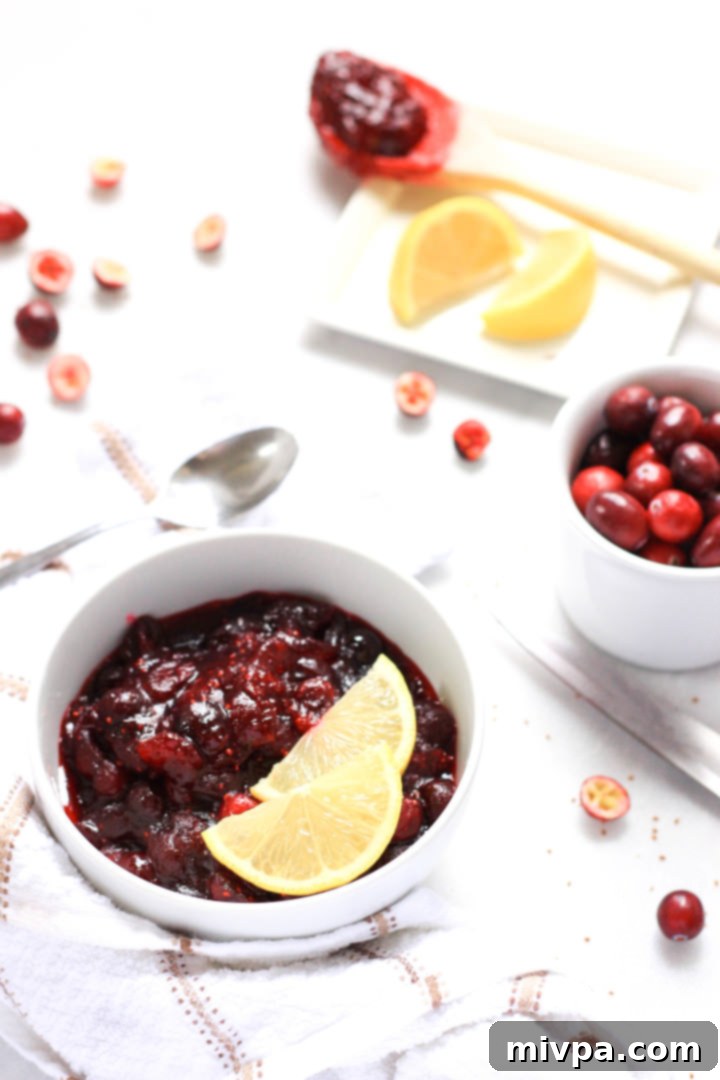 20-Minute Homemade Cranberry Sauce (Gluten-Free, Vegan) A bowl of gluten-free cranberry sauce with fresh cranberries at the side.
