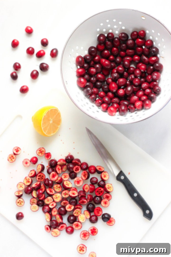 Gluten-Free Dairy-Free Cranberry Sauce (Vegan) Fresh cranberries cut into halves on a chopping board.