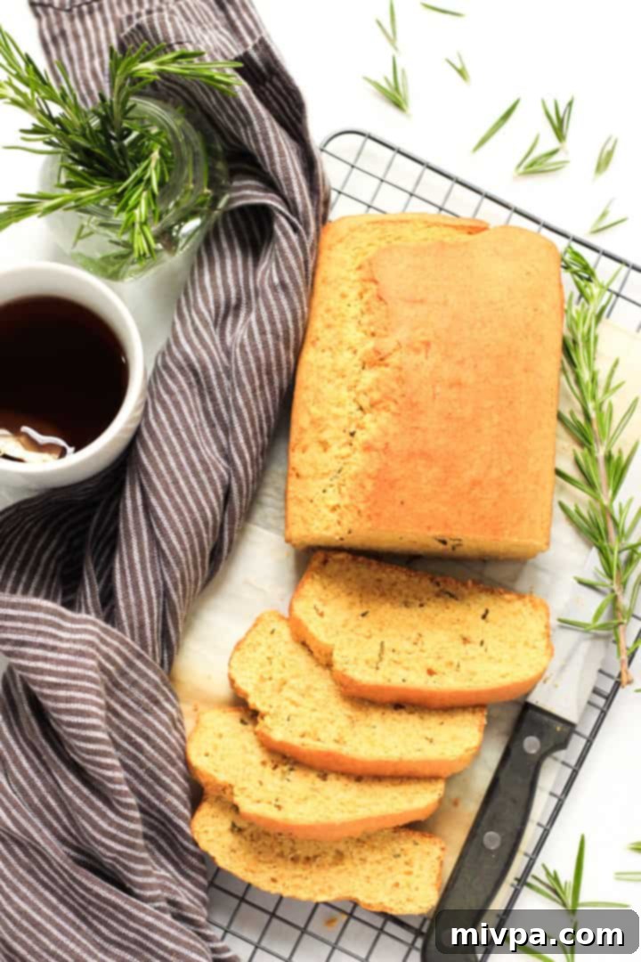 Top down view of a loaf of sliced rosemary cornbread on a cooling rack.