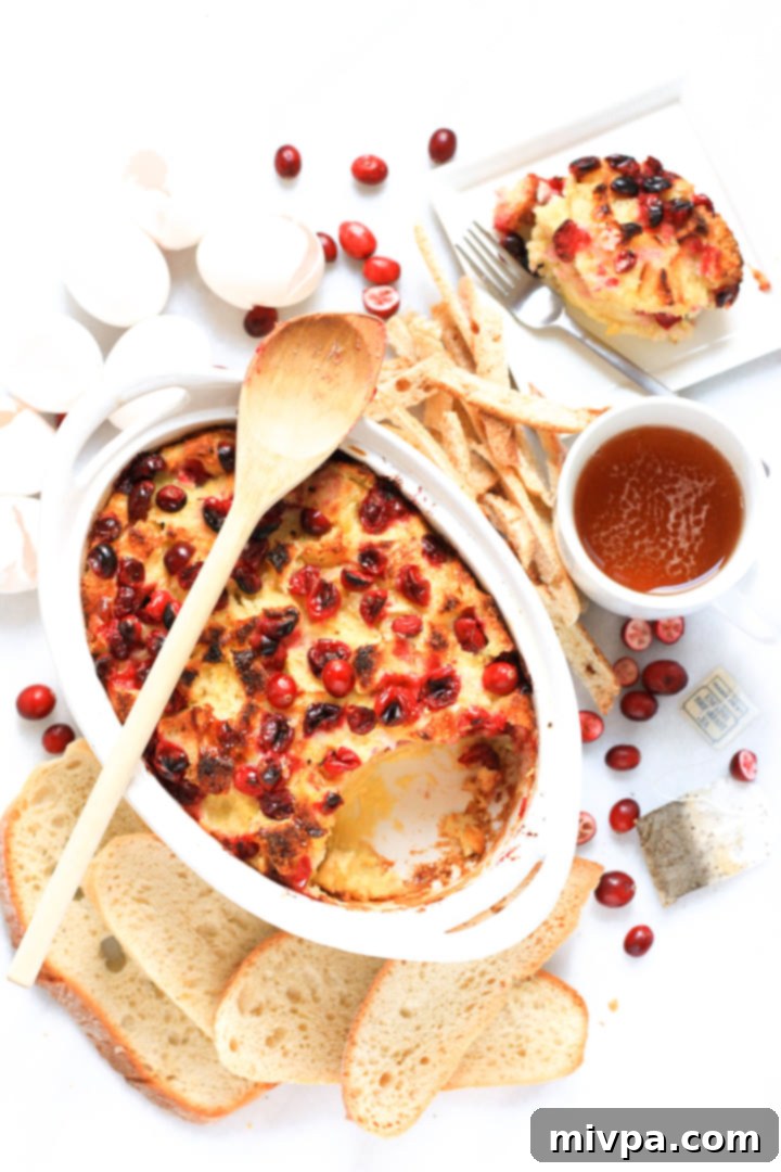 Cranberry Bread Pudding (Gluten-Free, Dairy-Free) A large casserole dish filled with baked cranberry bread pudding, alongside a cozy cup of tea, ready for serving.
