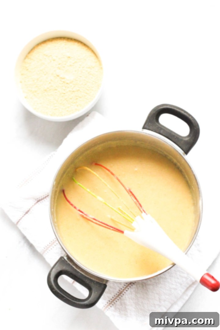 A pot with polenta and a whisk.
