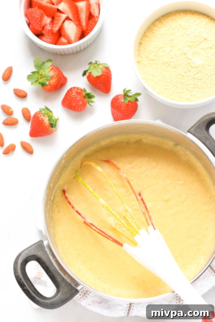 A whisk in a large pot of creamy breakfast polenta.