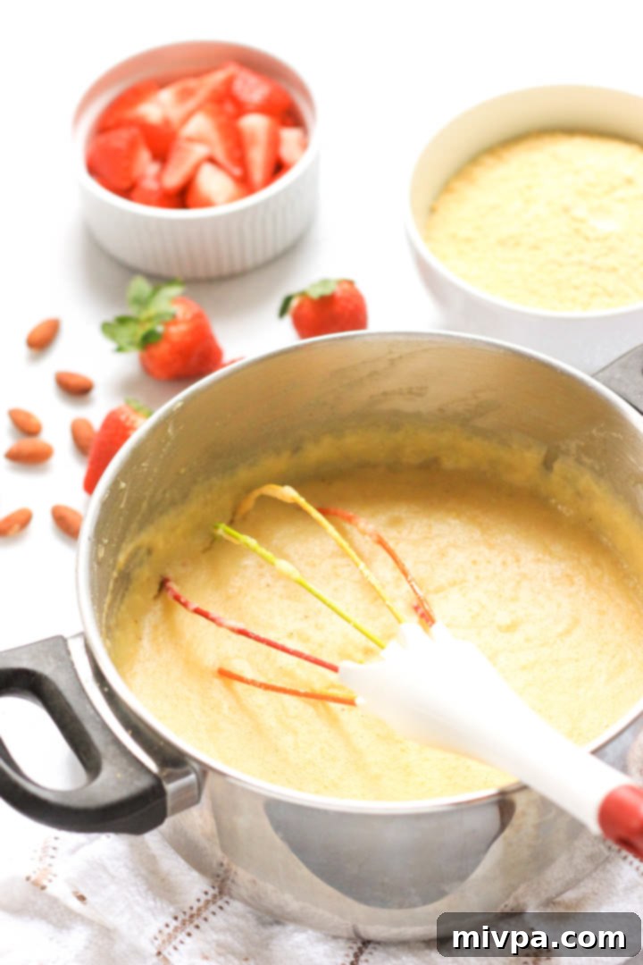 Whisking polenta porridge in a metal pot.