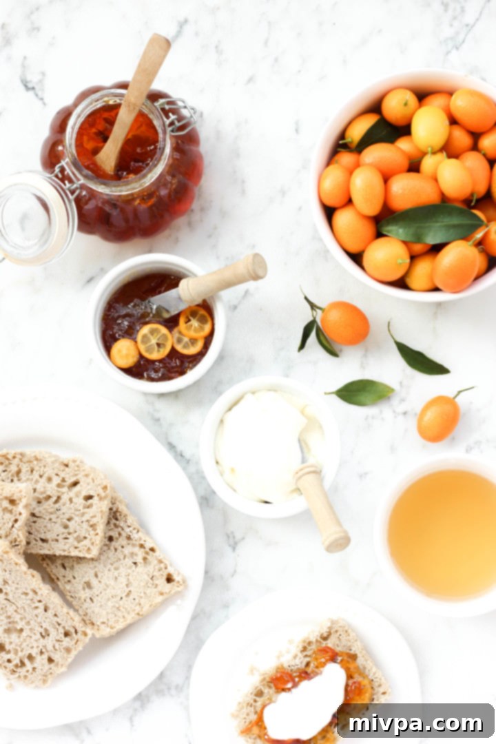 Easy Kumquat Marmalade Recipe (Gluten-Free, Vegan, Pectin-Free) Bread slices, a jar of kumquat marmalade, and fresh kumquats on a marble board. A rustic arrangement showcasing the versatility of homemade kumquat marmalade as a breakfast spread.