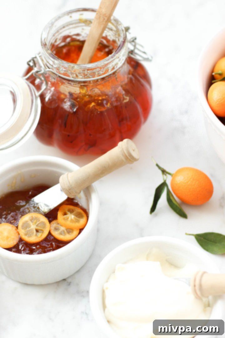 Easy Kumquat Marmalade Recipe (Gluten-Free, Vegan, Pectin-Free) Kumquat jam on marble board. A beautifully set jar of kumquat marmalade, showcasing its golden color and texture, ready to be enjoyed.