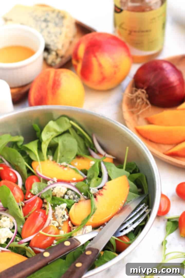 A bowl of fresh ingredients: peaches, arugula, cherry tomatoes, and red onion, ready for the salad.