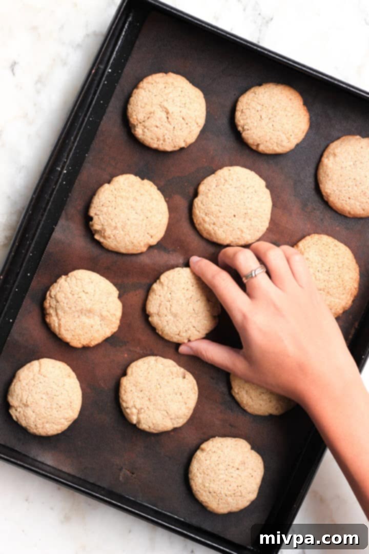 Easy Buckwheat Cookies (Gluten-Free, Dairy-Free) Picking up a freshly baked cookie from a baking sheet.