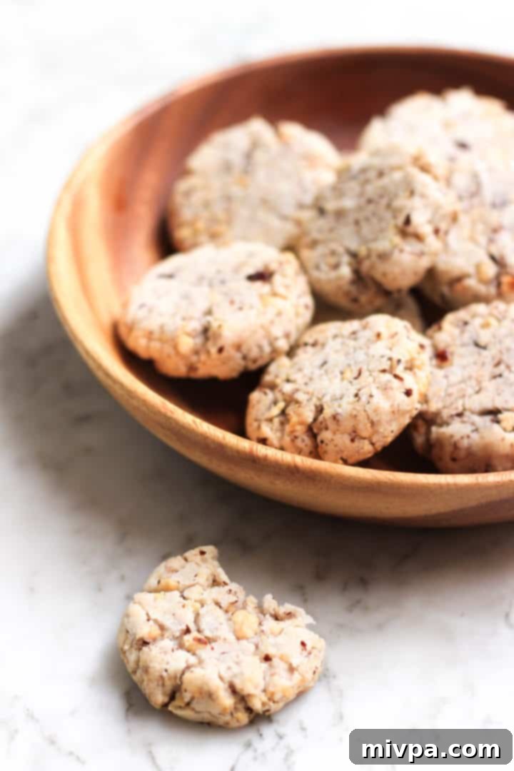 A delicious hazelnut cookie broken in half, showing its crispy texture and hazelnut pieces.