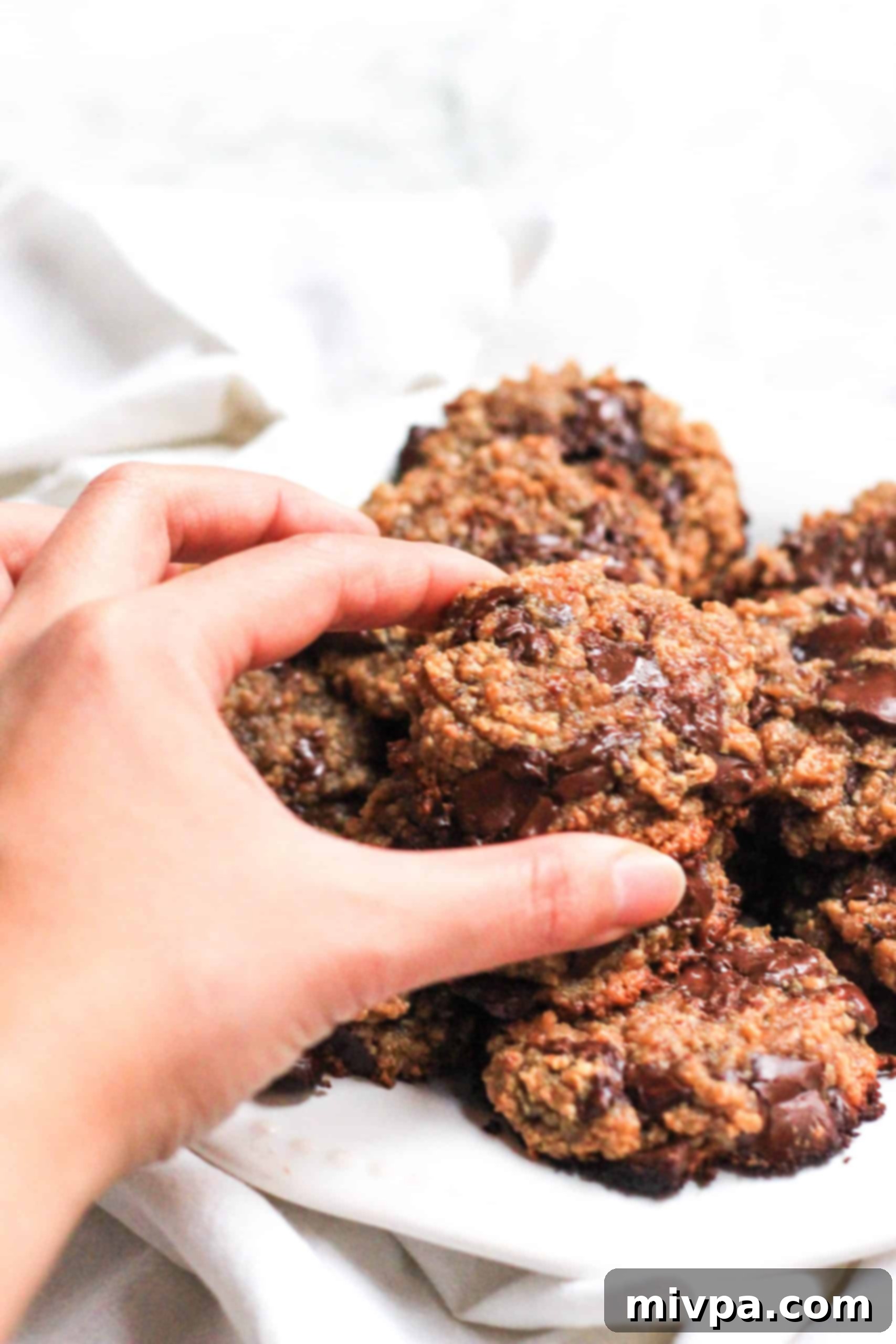 Vegan Cashew Butter Cookies (Gluten-Free) Hand reaching for a cookie from a plate of gluten-free cashew butter cookies.
