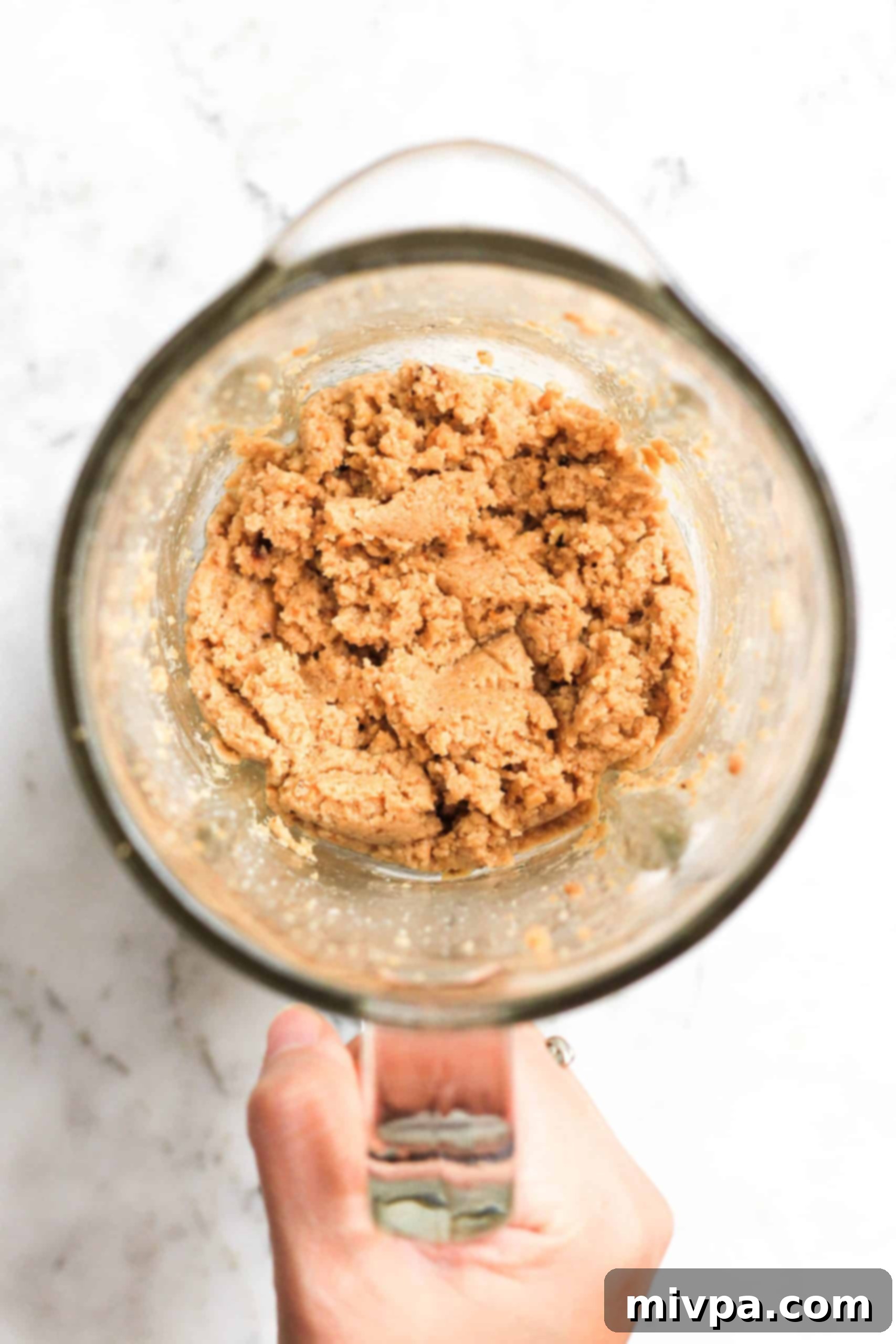 Gluten-Free Cashew Butter Cookies (Vegan) Hand holding a blender with cashew butter.