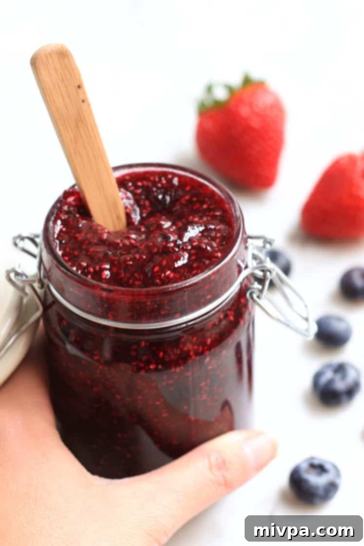 Mixed Berry Chia Seed Jam (Gluten-Free, Vegan) Hand holding a jar of homemade mixed berry chia seed jam.