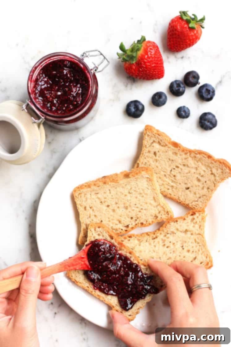 Mixed Berry Chia Seed Jam (Gluten-Free, Vegan) Spreading homemade mixed berry chia seed jam on a slice of golden toast.