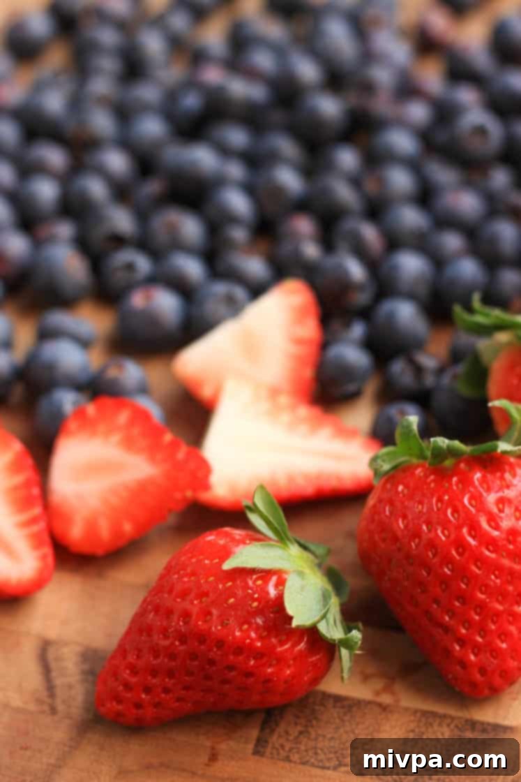 Mixed Berry Jam Recipe (Gluten-Free, Vegan) Fresh strawberries and blueberries neatly arranged on a wooden chopping board.