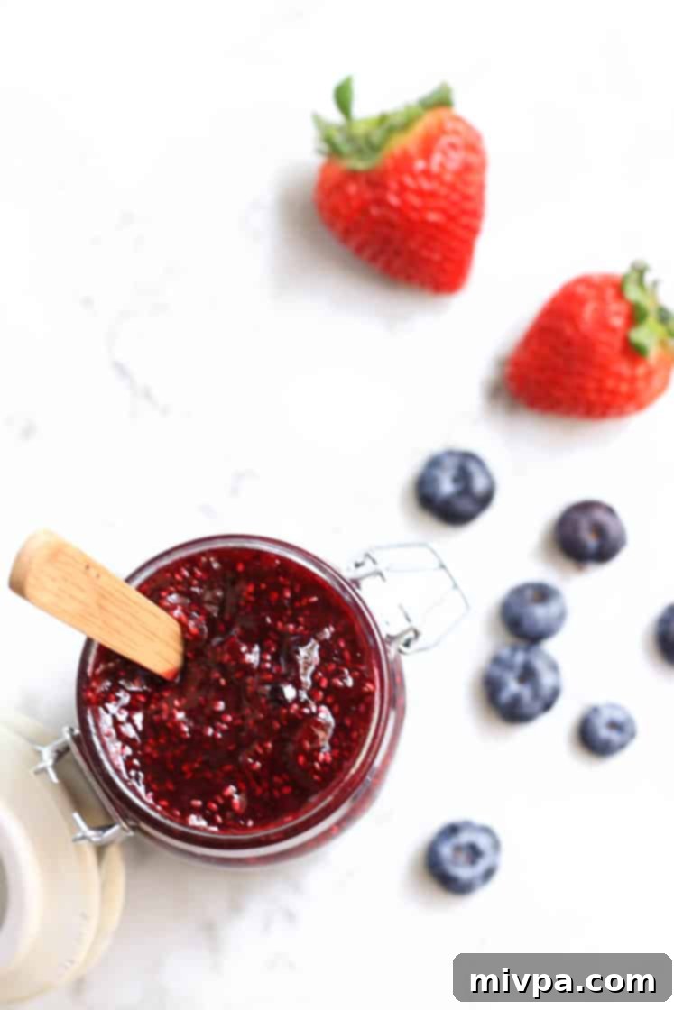 Mixed Berry Preserves (Gluten-Free, Vegan) Top down view of a glass jar filled with mixed berry chia seed jam, surrounded by fresh berries.
