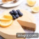A slice of creamy lemon cheesecake on a plate with fresh berries.