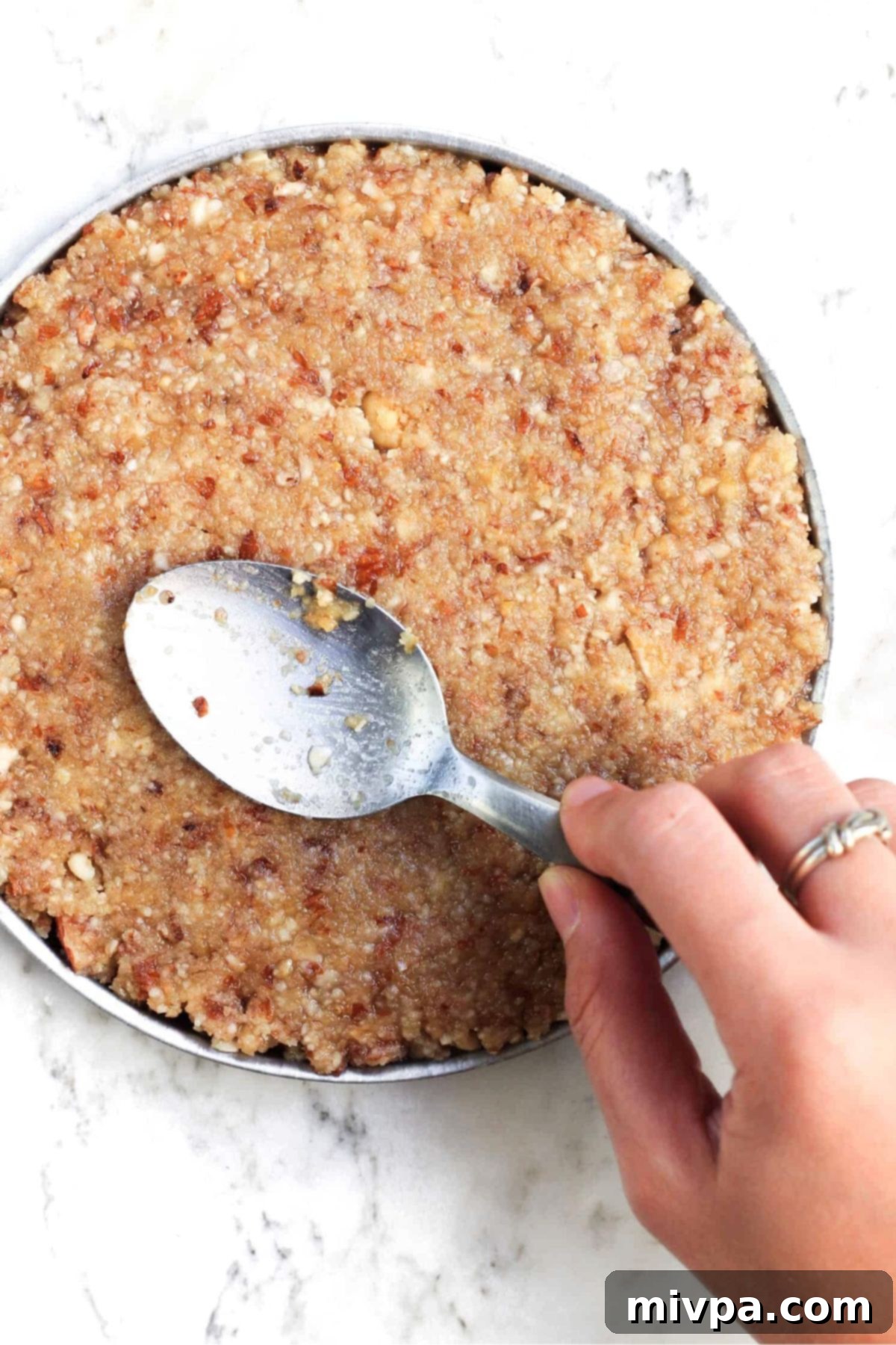 Pressing processed nuts into cake pan.