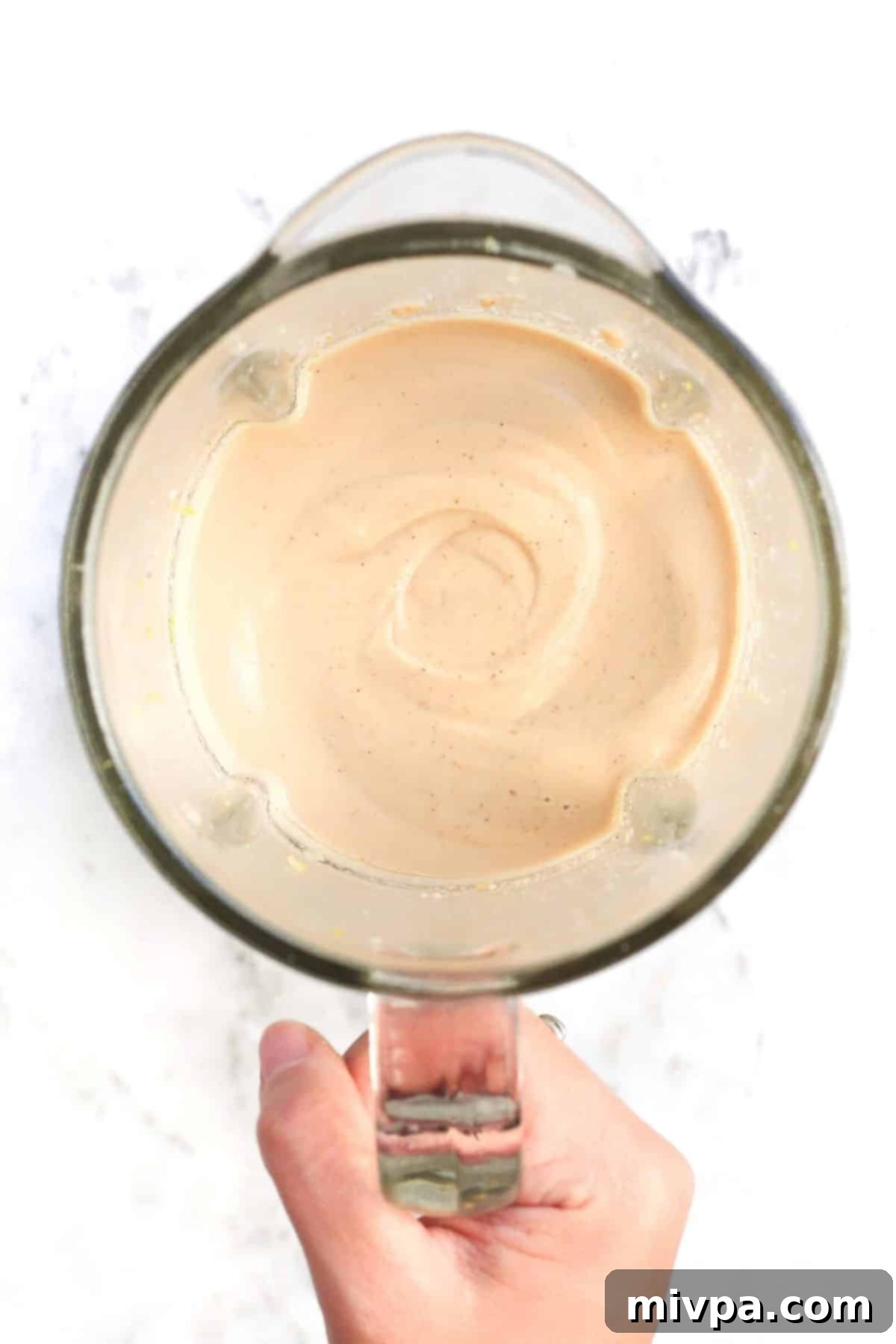 Holding a high-speed blender with processed cashews.