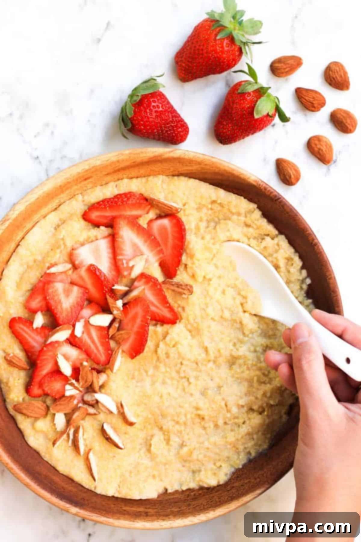 Top down view of bowl of creamy millet porridge with fresh strawberries.
