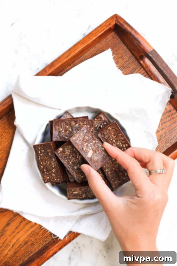 Easy Homemade Chocolate (Gluten-free, Vegan) Hand picking up a piece of homemade chocolate from a bowl of chocolates.