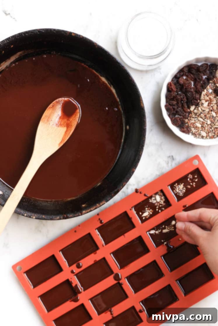 Easy Homemade Chocolate (Gluten-free, Vegan) Sprinkling seeds over chocolate mixture in a silicon mold for homemade chocolate.