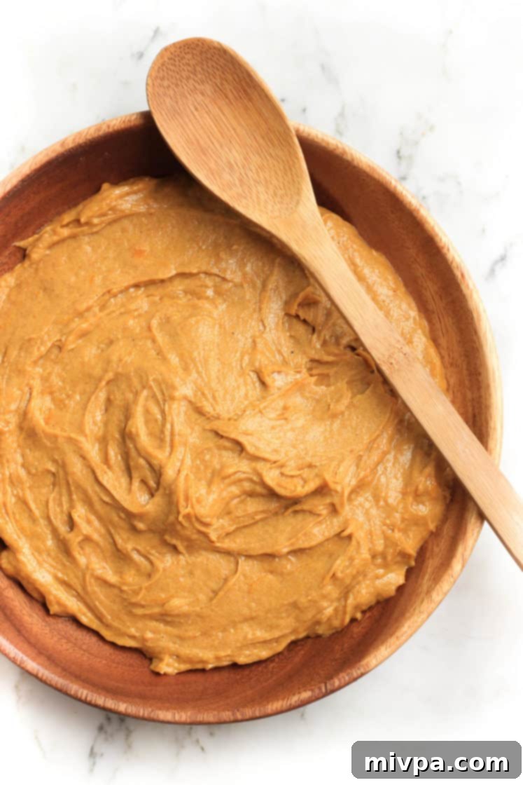 Smooth and homogenous pumpkin muffin batter, perfectly mixed in a wooden bowl, ready for baking.