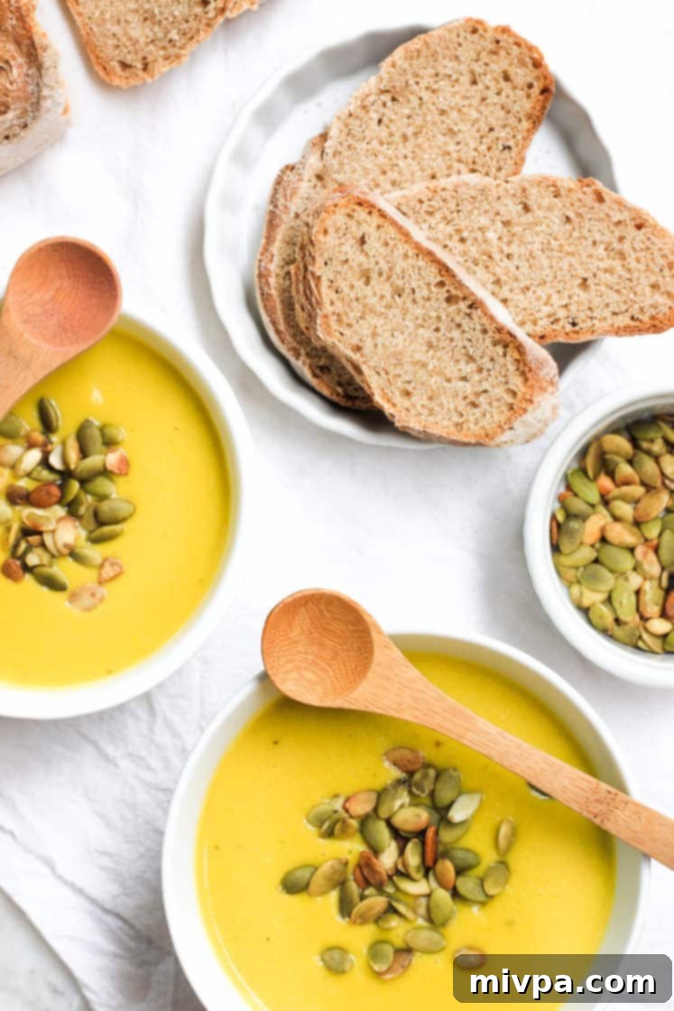 Creamy Gluten-Free Pumpkin Soup (Dairy-free, Vegan) Top down shot of a table with bowls of soup and bread.