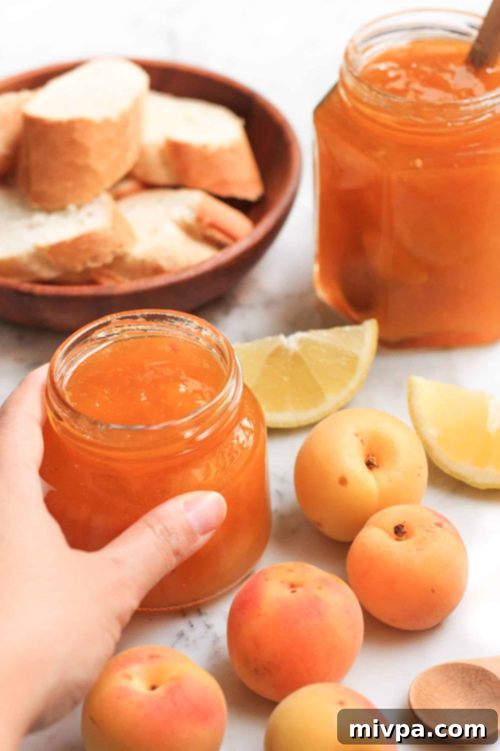 Hand reaching for a jar of homemade apricot jam.