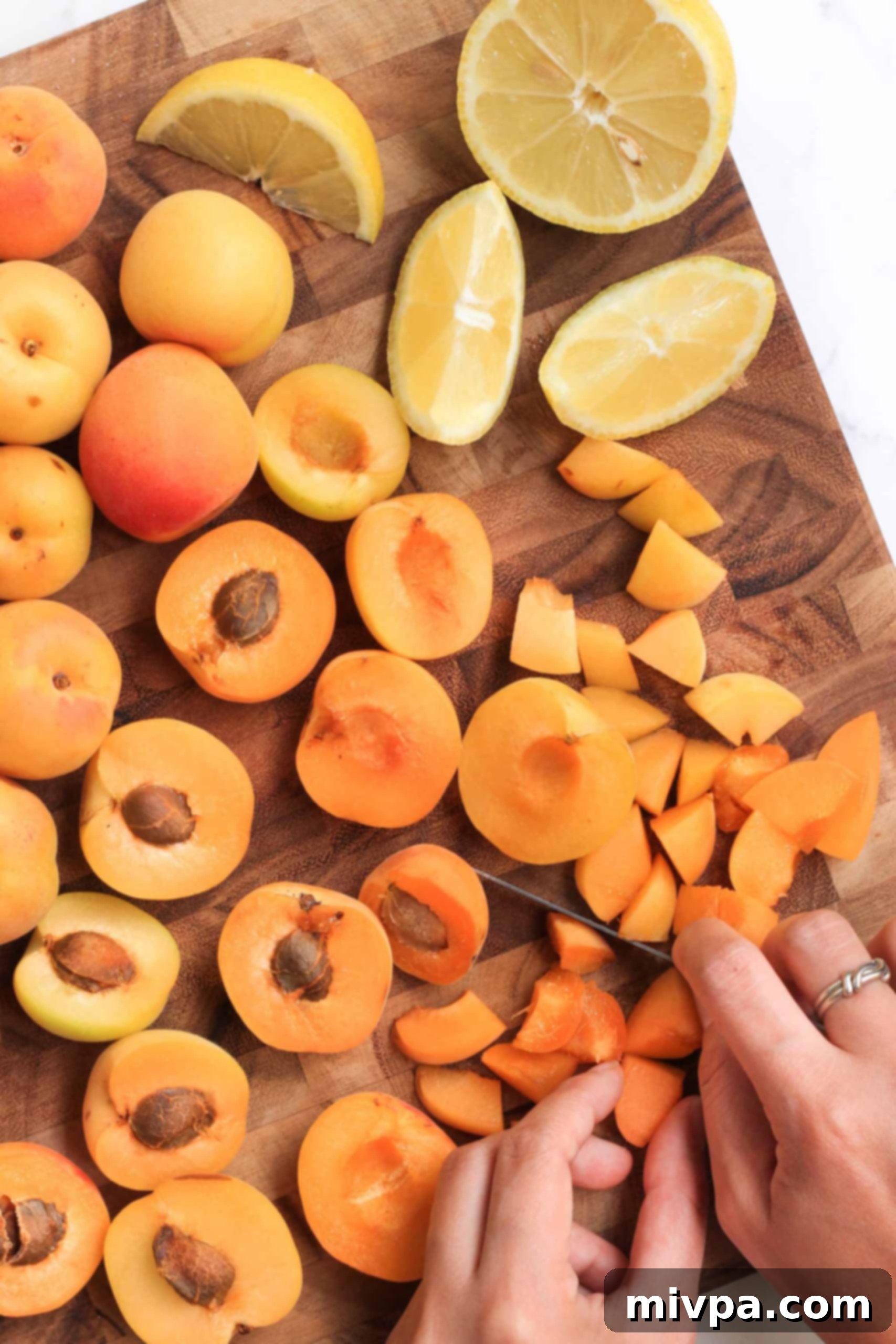 Slicing apricots into small pieces on a wooden board.