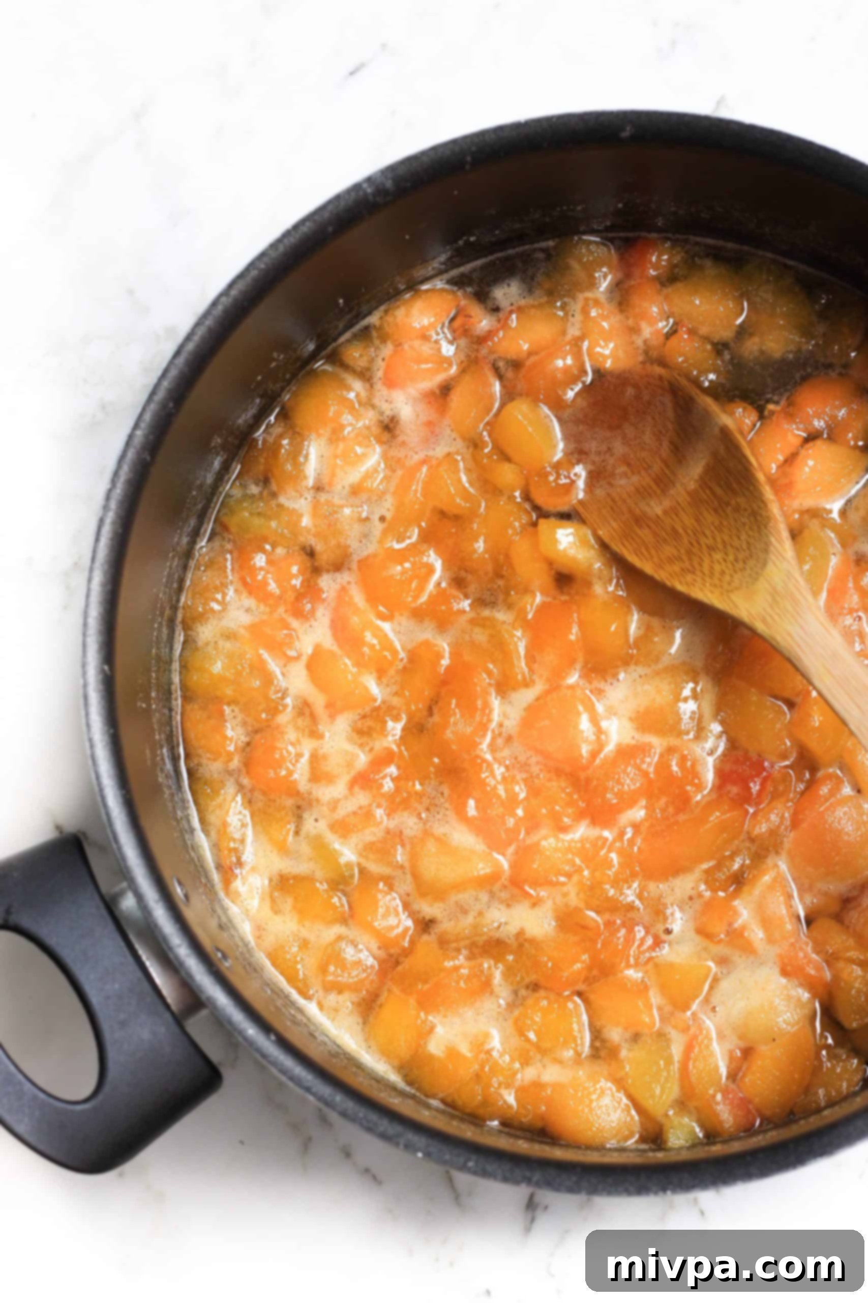 Stirring homemade apricot preserves in a large pot.