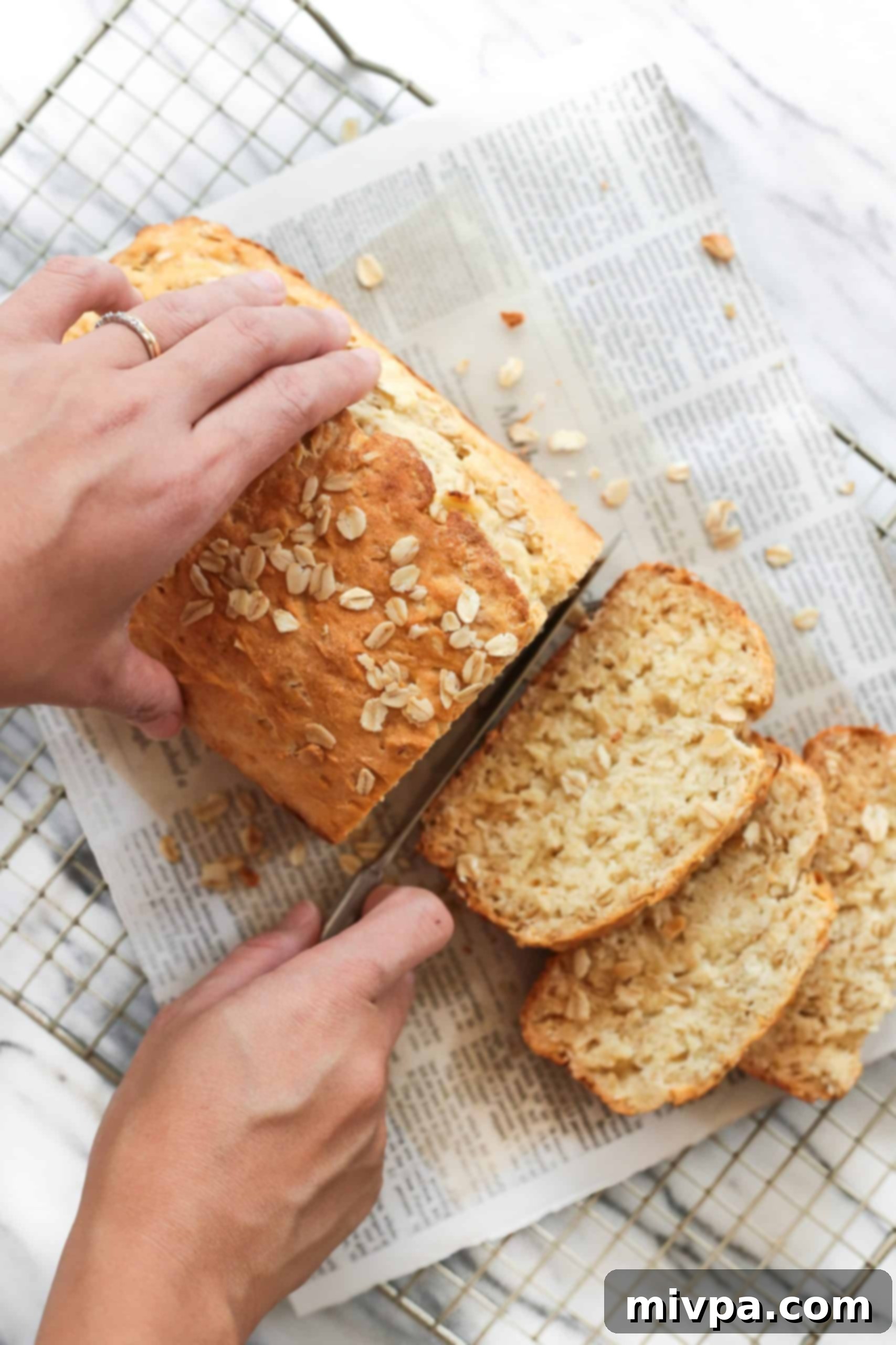 A hand slicing into a perfectly baked loaf of gluten-free oat bread on a cutting board.